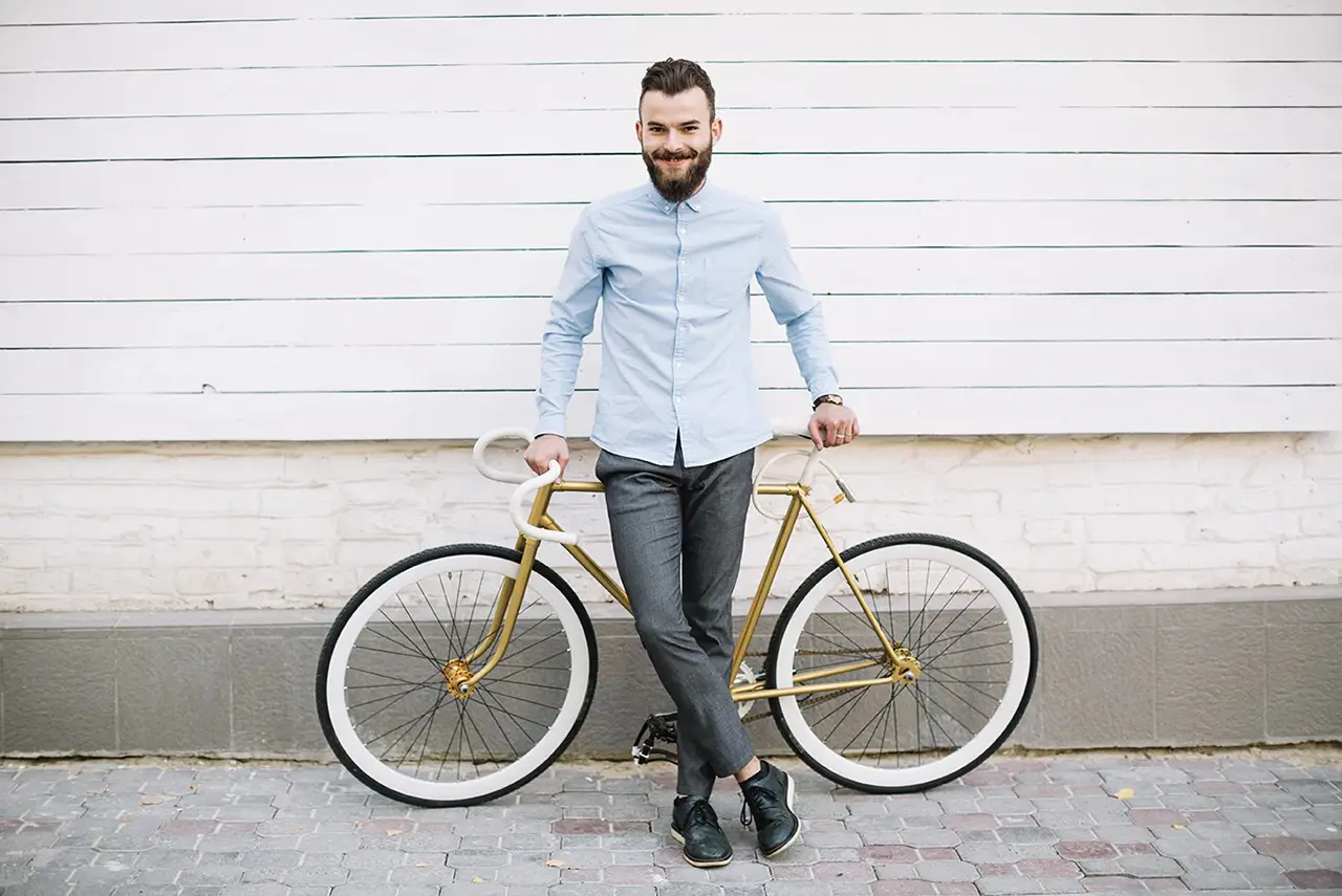 Man standing with a bicycle against a white wall