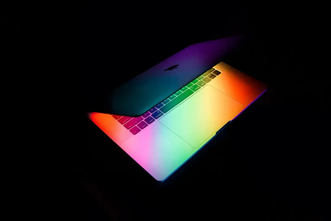 Partially open laptop glowing with rainbow light