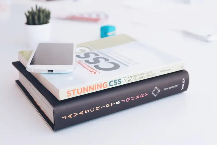 Two coding books stacked with a smartphone on top